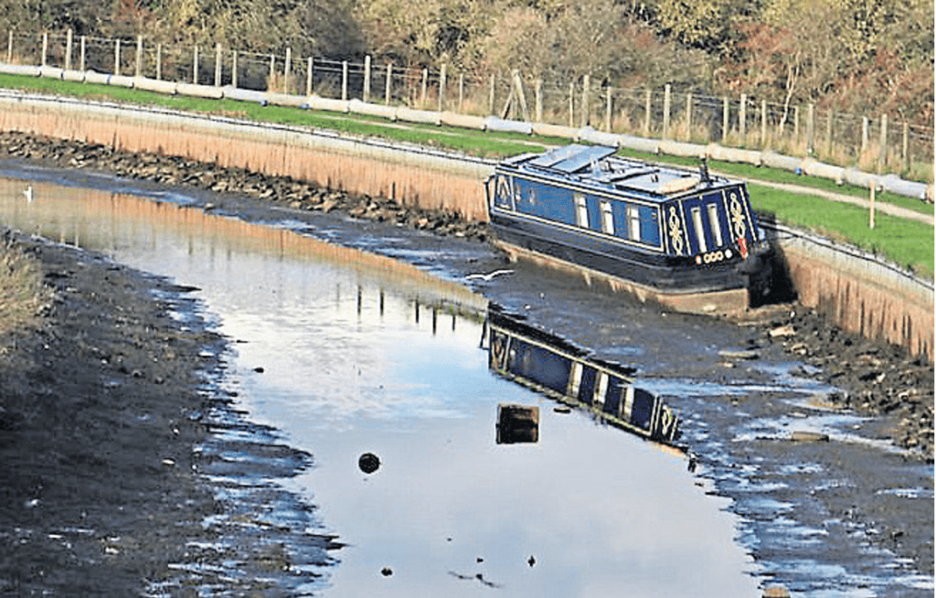 A solitary narrowboat stranded within the dry section of the canal.