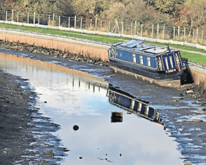 A solitary narrowboat stranded within the dry section of the canal.