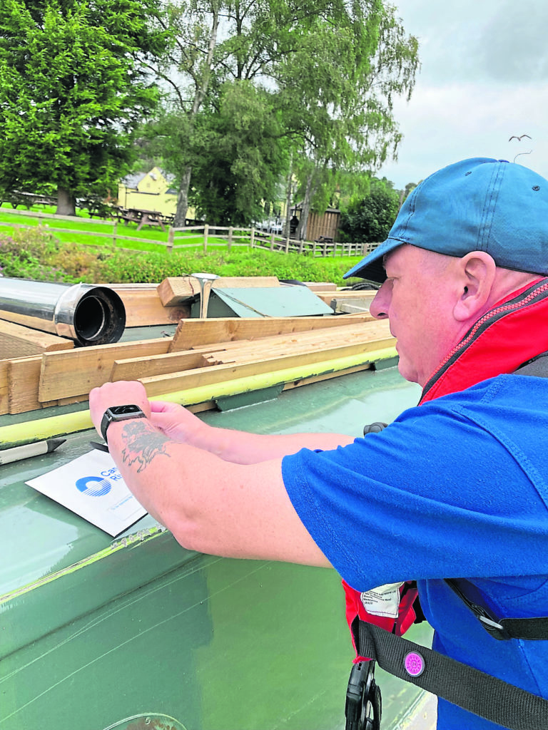 Steve fastens a patrol notice to the roof of a narrowboat.